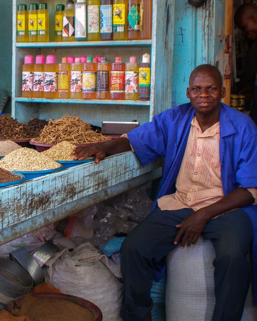 Un vendeur assis près de son étal de céréales et de sa balance, à Bamako